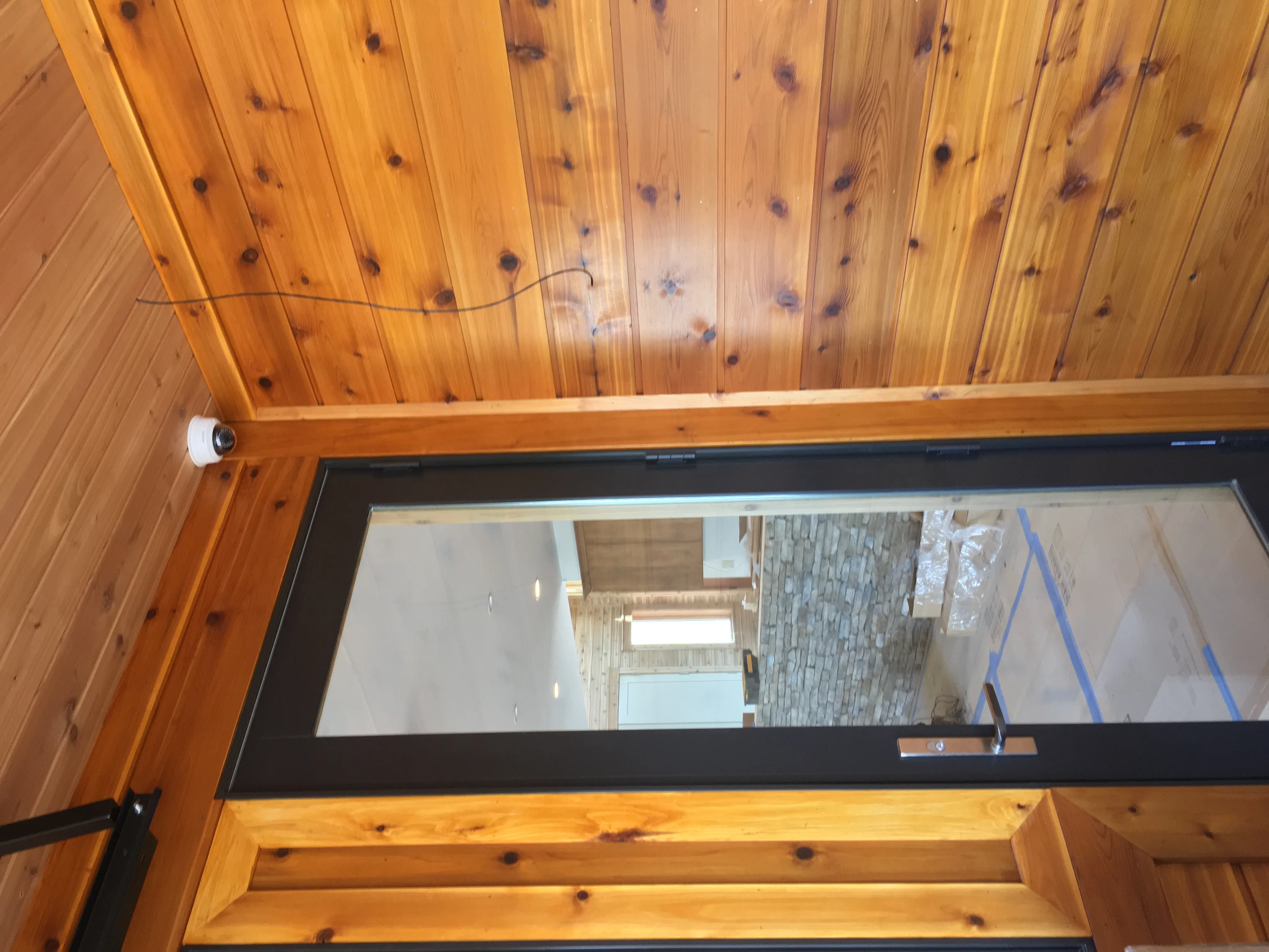 Ceiling-mounted surveillance camera above a glass entry door