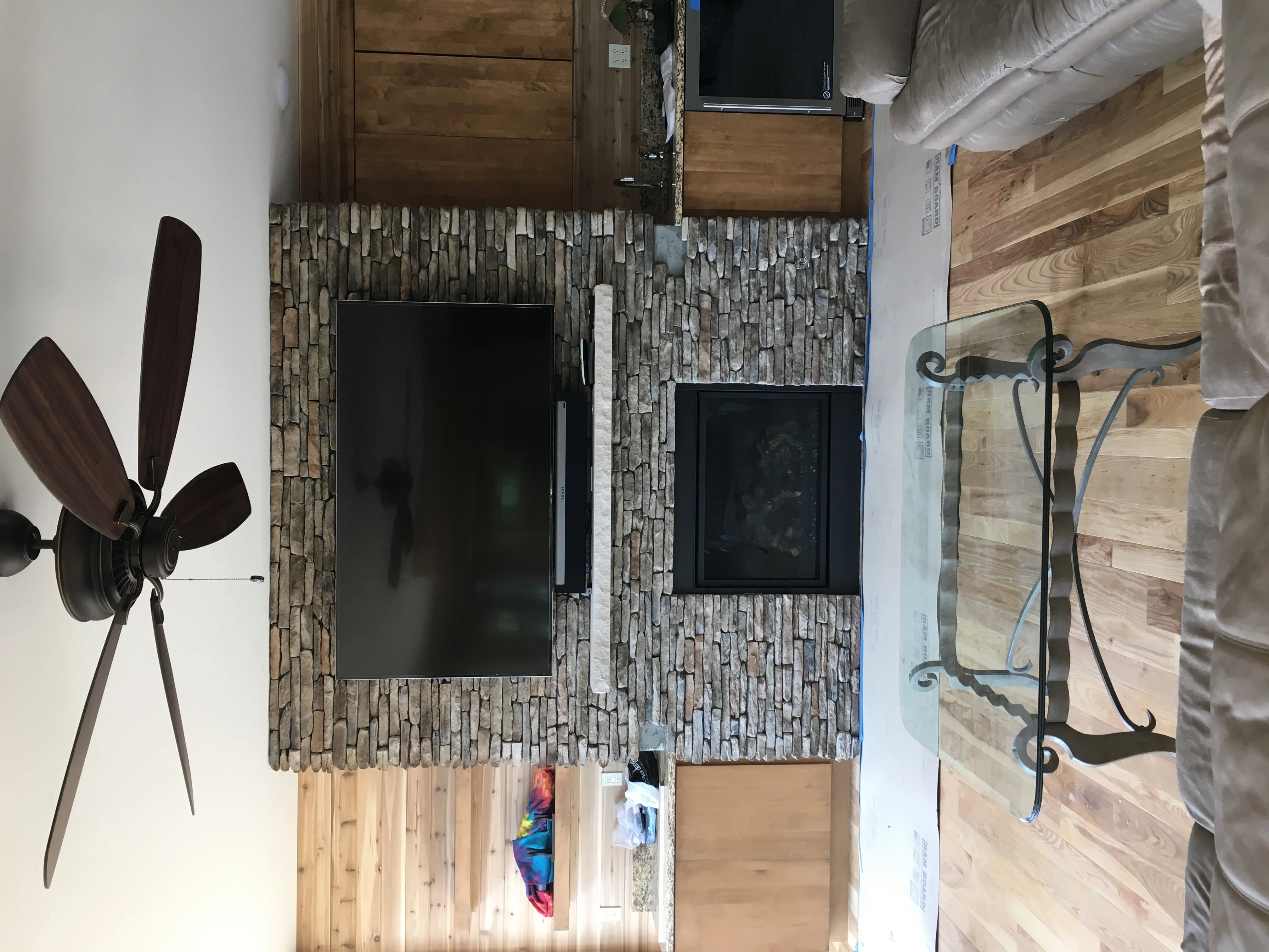 Large television and soundbar installed over a central stone fireplace